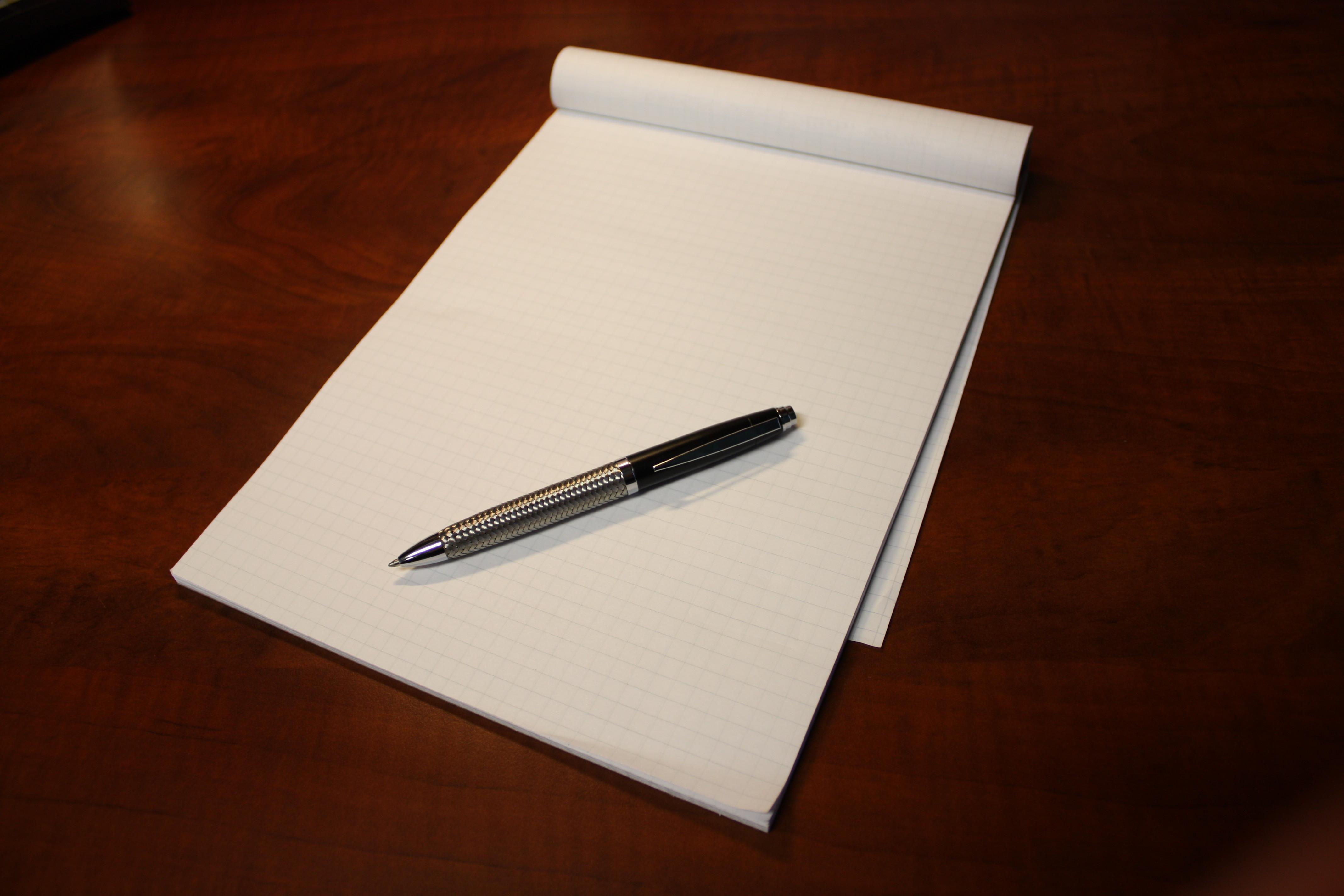 Белый лист бумаги на столе. Бумага лежит с ручкой. С чистого листа. Ручка лежит. Белый лист на столе.